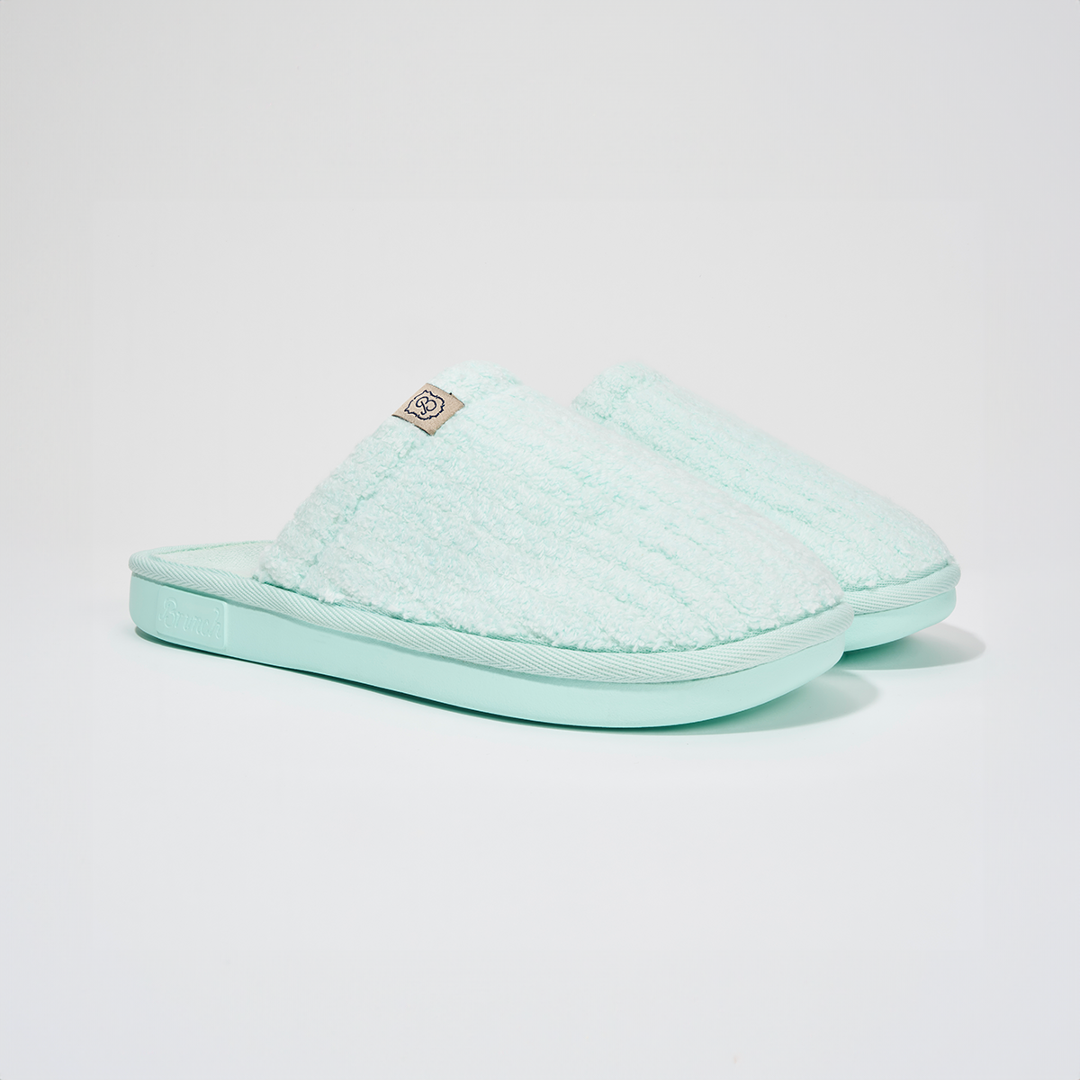 Angled view of Lido Essential slipper in aqua showcasing ribbed terry upper, low open-back silhouette, and cushioned foam sole on white background