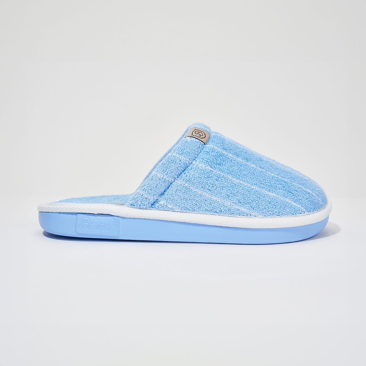 Side view of The Essential slipper in Cabana striped terry showing white trim and blue sole on white
