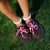 Top-down view of Carrie Charm Kit hot pink paracord laces with beads laced onto brown suede boat mules on grass
