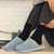 Side view of navy cashmere-wool socks showcasing ribbed knit texture and mid-calf height with light blue slippers and white brick background