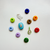Top-down view of Carrie Charm Kit showing multicolor donut beads, a white fish charm, and turquoise and green rhinestone charms on a white background