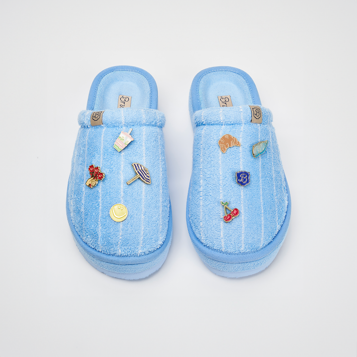 Top-down view of Essential XXL slippers in Cabana blue striped terry showcasing attached magnetic charms on a white background
