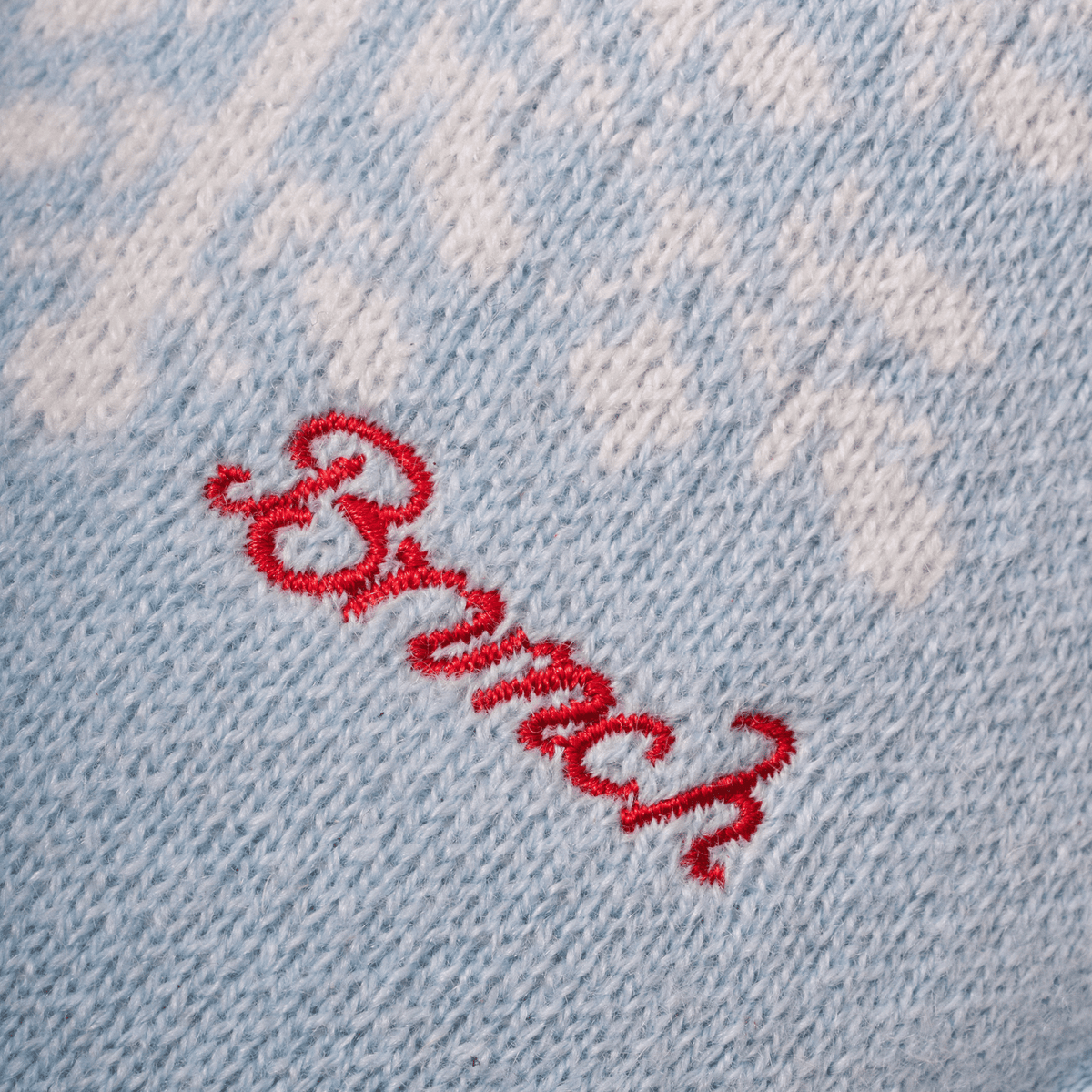 Close-up of Essential Cashmere slipper upper showing light blue knit cashmere texture and red embroidered Brunch logo