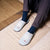 Top-down view of Essential Cashmere slipper in blue showcasing white snowflake motif and red Brunch embroidery on an indoor rug background