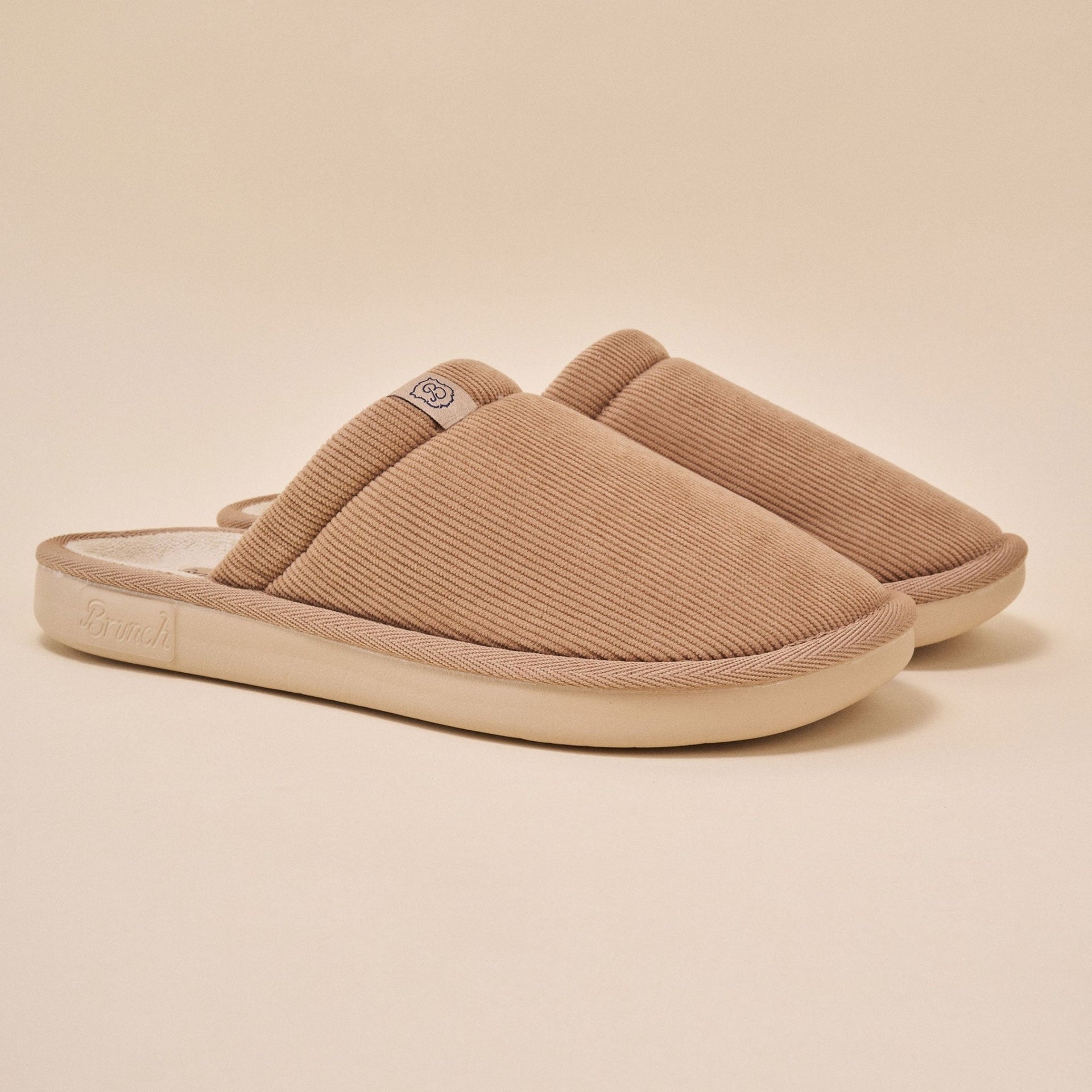 Side view of Essential Corduroy slipper in caramel showing ribbed corduroy upper and low profile outsole on beige background