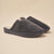 Angled view of Essential slipper, dark grey terry, closed-toe padded upper and molded EVA sole on beige background