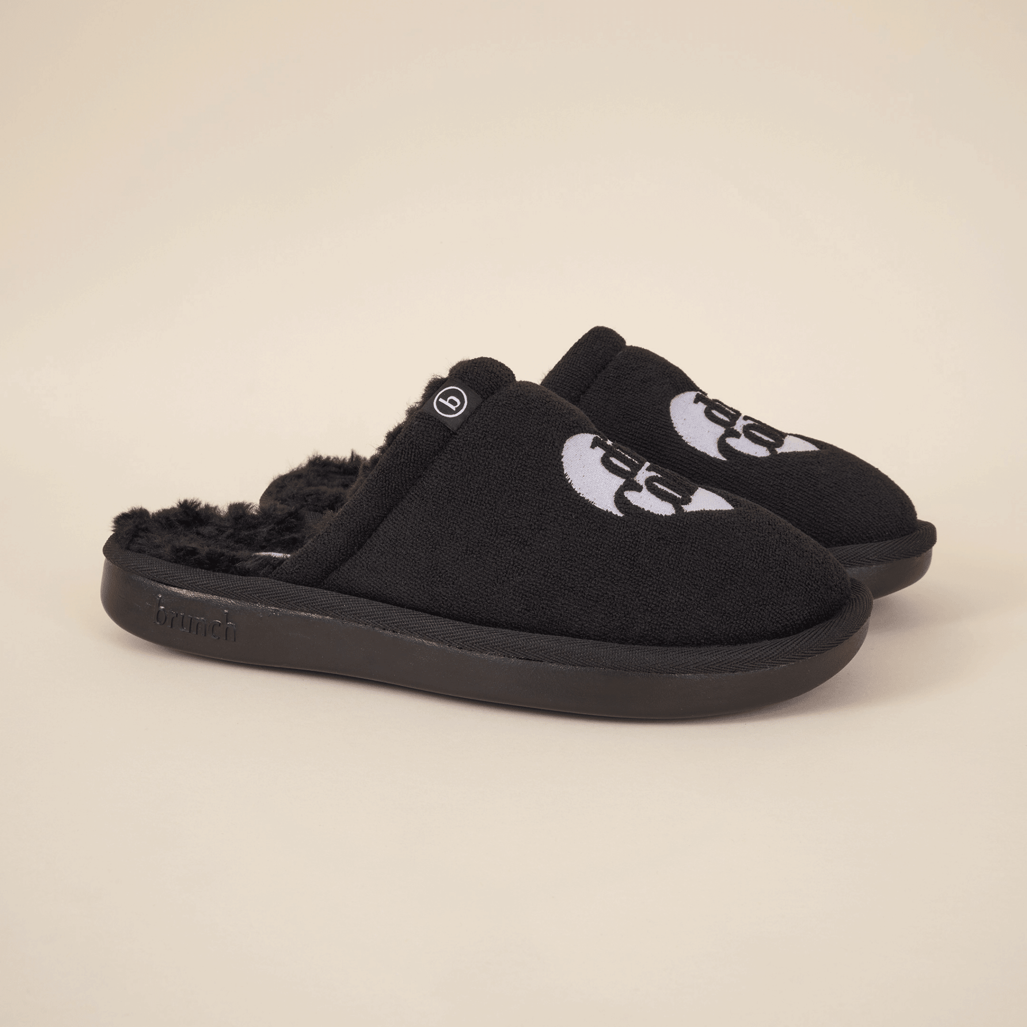 Three-quarter view of black Diet Coke x Brunch shearling slippers with faux-shearling lining, embroidered logo, and black sole