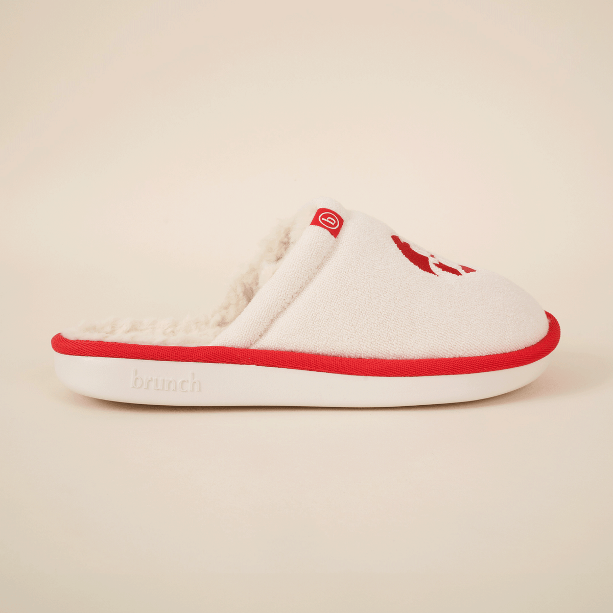 Side view of Diet Coke shearling slipper showing cream upper, faux shearling lining, red trim and white sole on neutral background