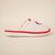 Side view of Diet Coke shearling slipper showing cream upper, faux shearling lining, red trim and white sole on neutral background