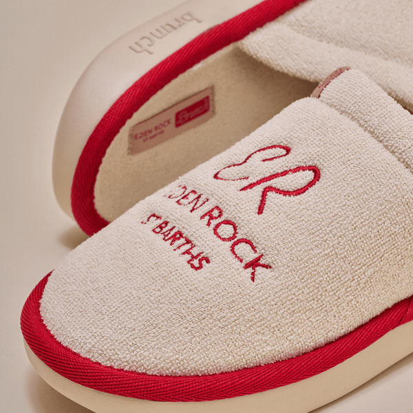 Close-up of beige Eden Rock slipper showcasing red embroidered Eden Rock St Barths logo and red trim on terry upper