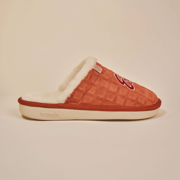 Side view of Essential Eggo slipper in syrup with waffle-embossed suede upper, shearling lining and cream outsole on neutral background