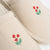 Top view of pair of beige canvas slippers showcasing hand stitched red wildflower embroidery on toes with white background
