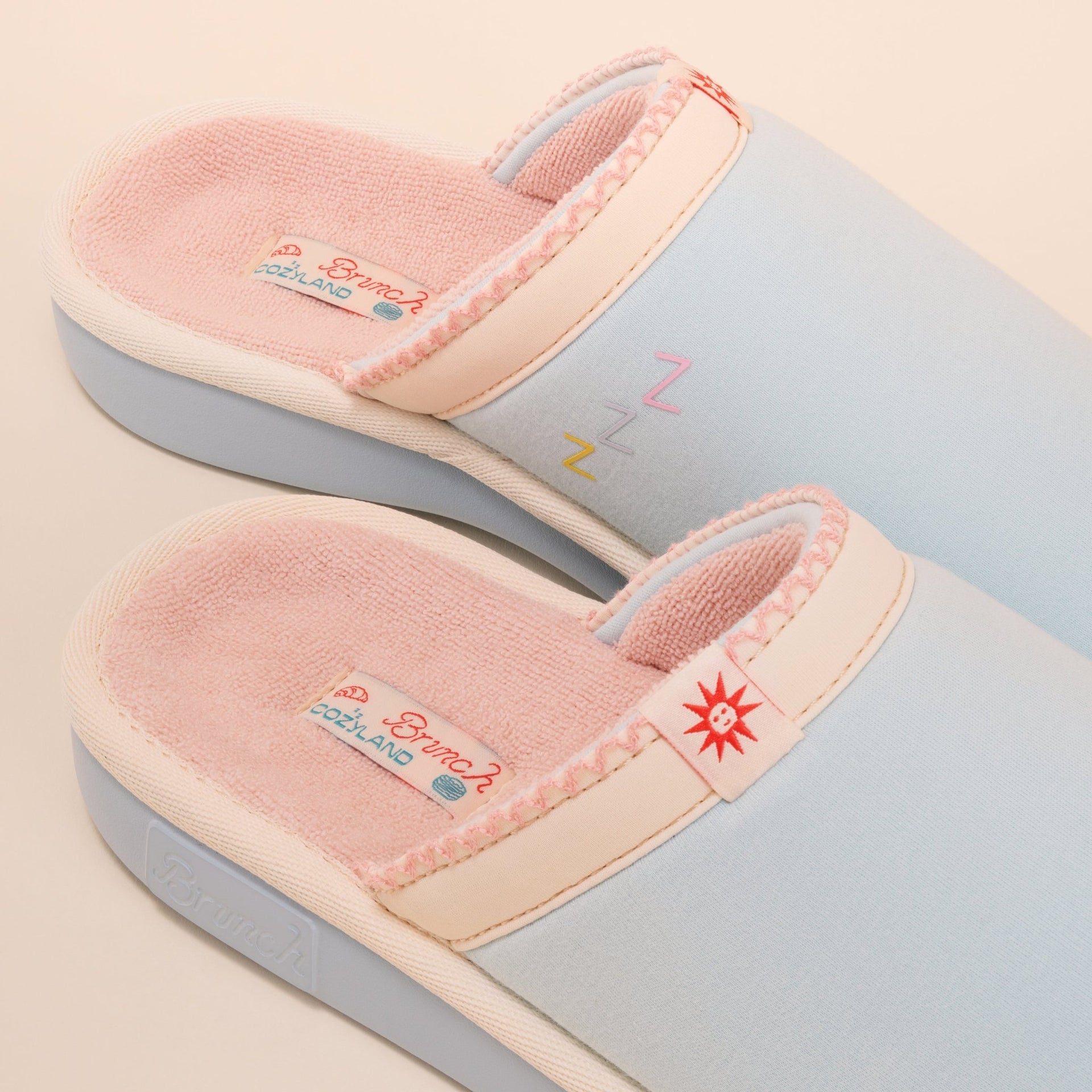 Angled close-up of French Blue Cozyland slip-on slipper showing pink terry lining, embroidered Zs and sun logo