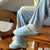 Side view of Essential Cozyland slipper in French Blue showing cushioned sole and trim, worn with patterned pajamas on a wooden chair