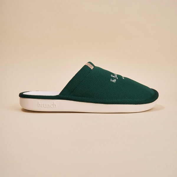 Side view of green Essential slipper with embroidered Beverly Hills Hotel logo and white EVA sole on beige background