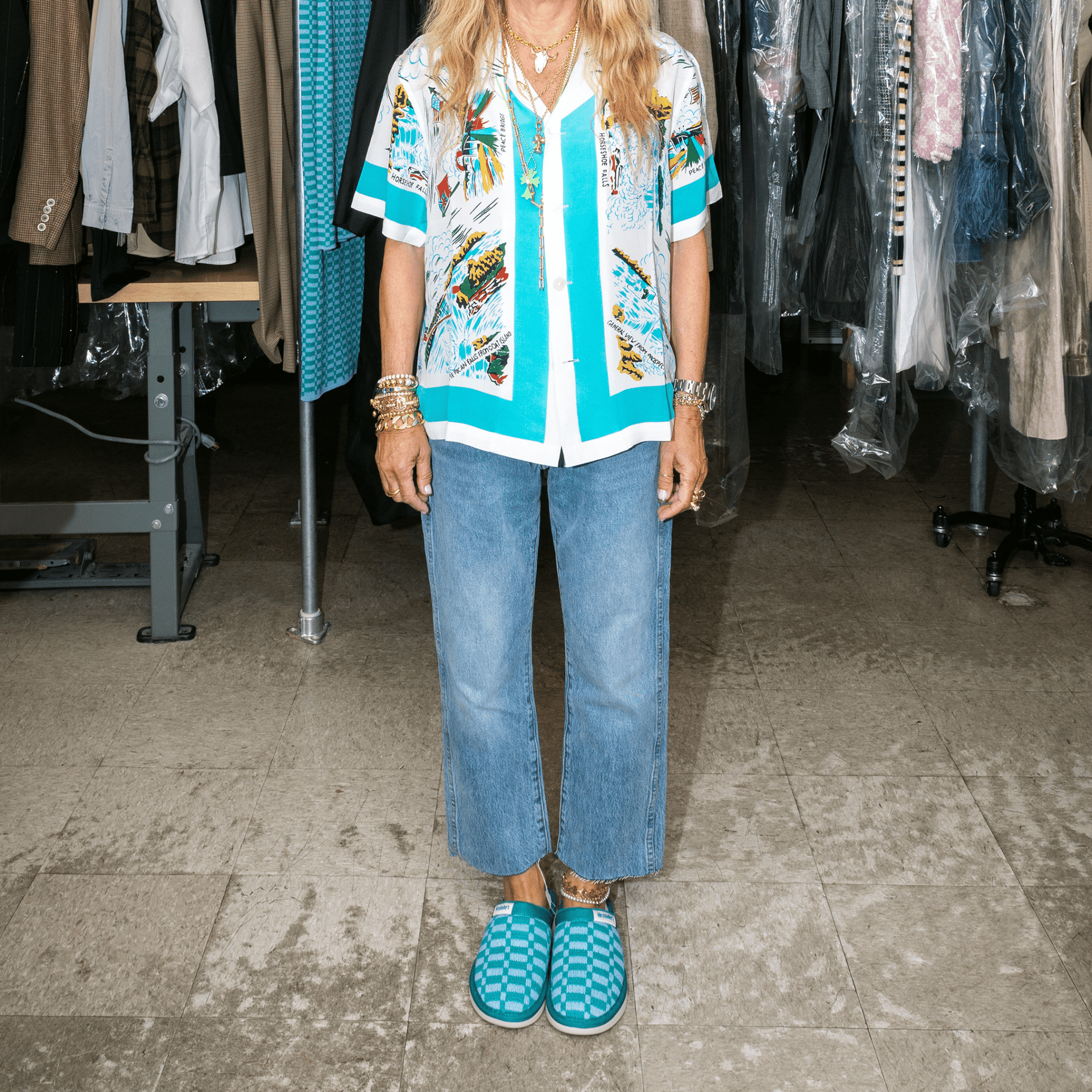Person standing wearing marine checkered Brunch x Hirshleifers slip-on slippers with cropped jeans in a studio wardrobe setting