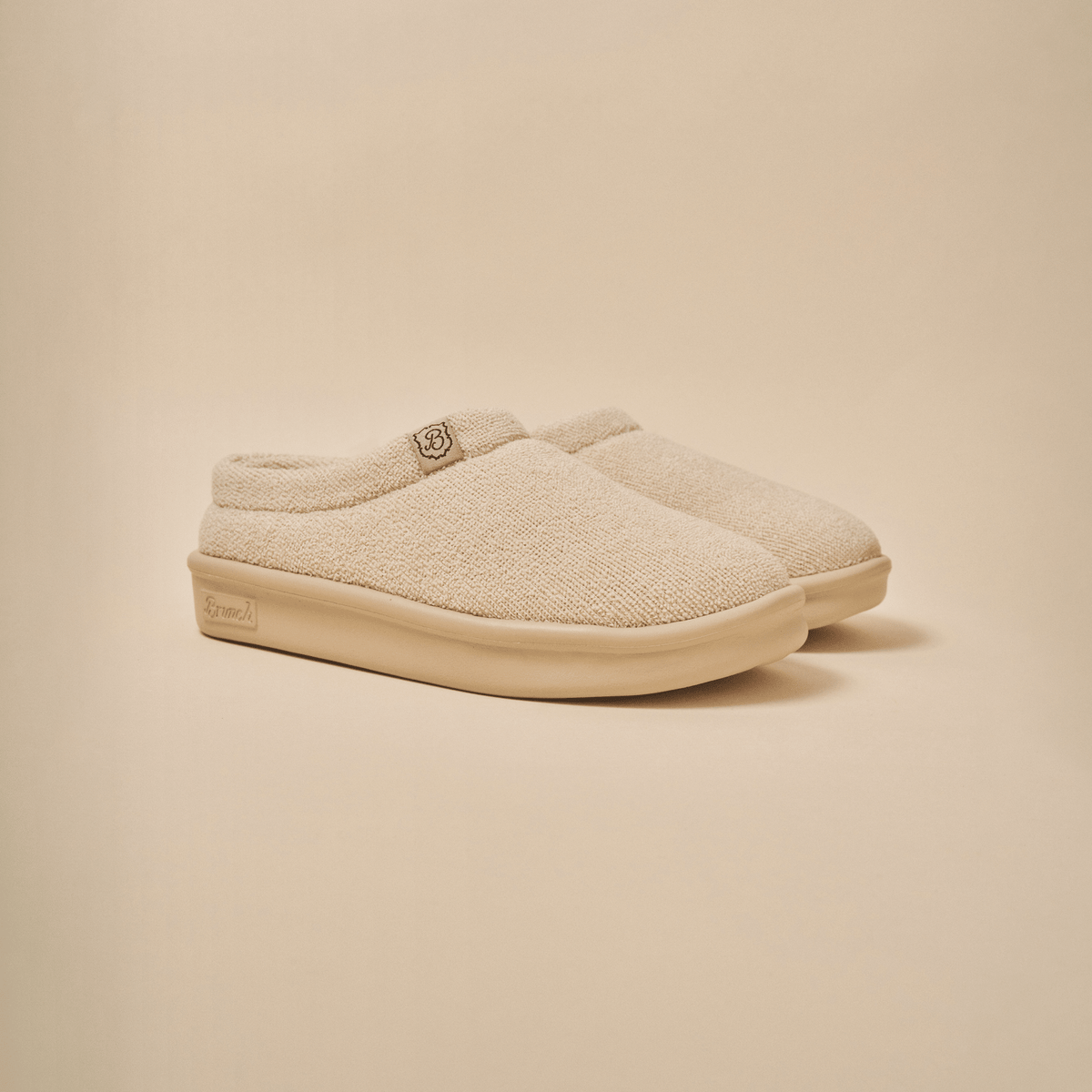 Three quarter view of Essential Kids slipper in beige terry with cushioned EVA sole on neutral background