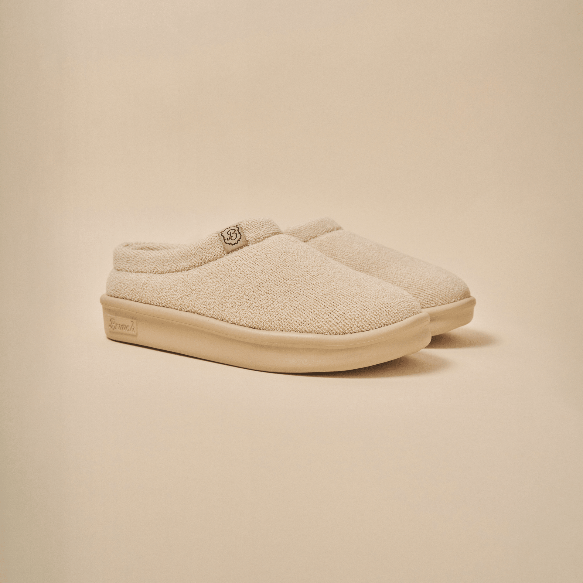 Three quarter view of Essential Kids slipper in beige terry with cushioned EVA sole on neutral background