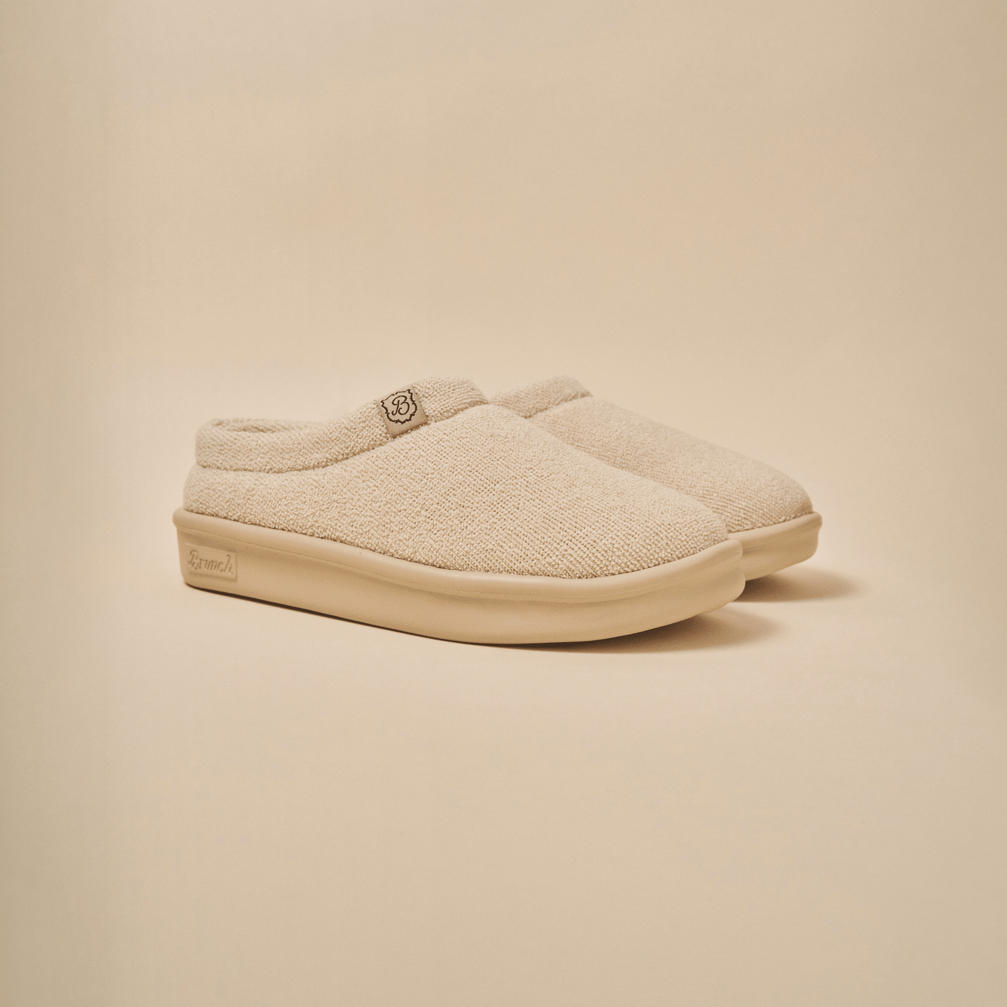 Three quarter view of Essential Kids slipper in beige terry with cushioned EVA sole on neutral background
