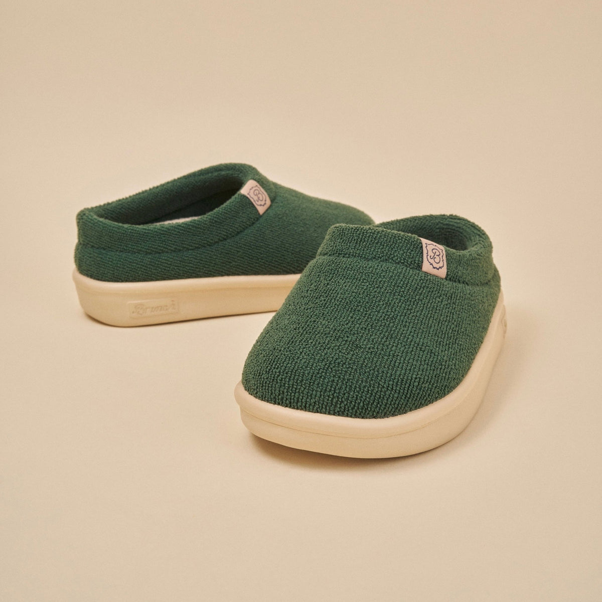 Front three-quarter view of Essential Kids slipper in emerald terry with cream EVA sole on beige background