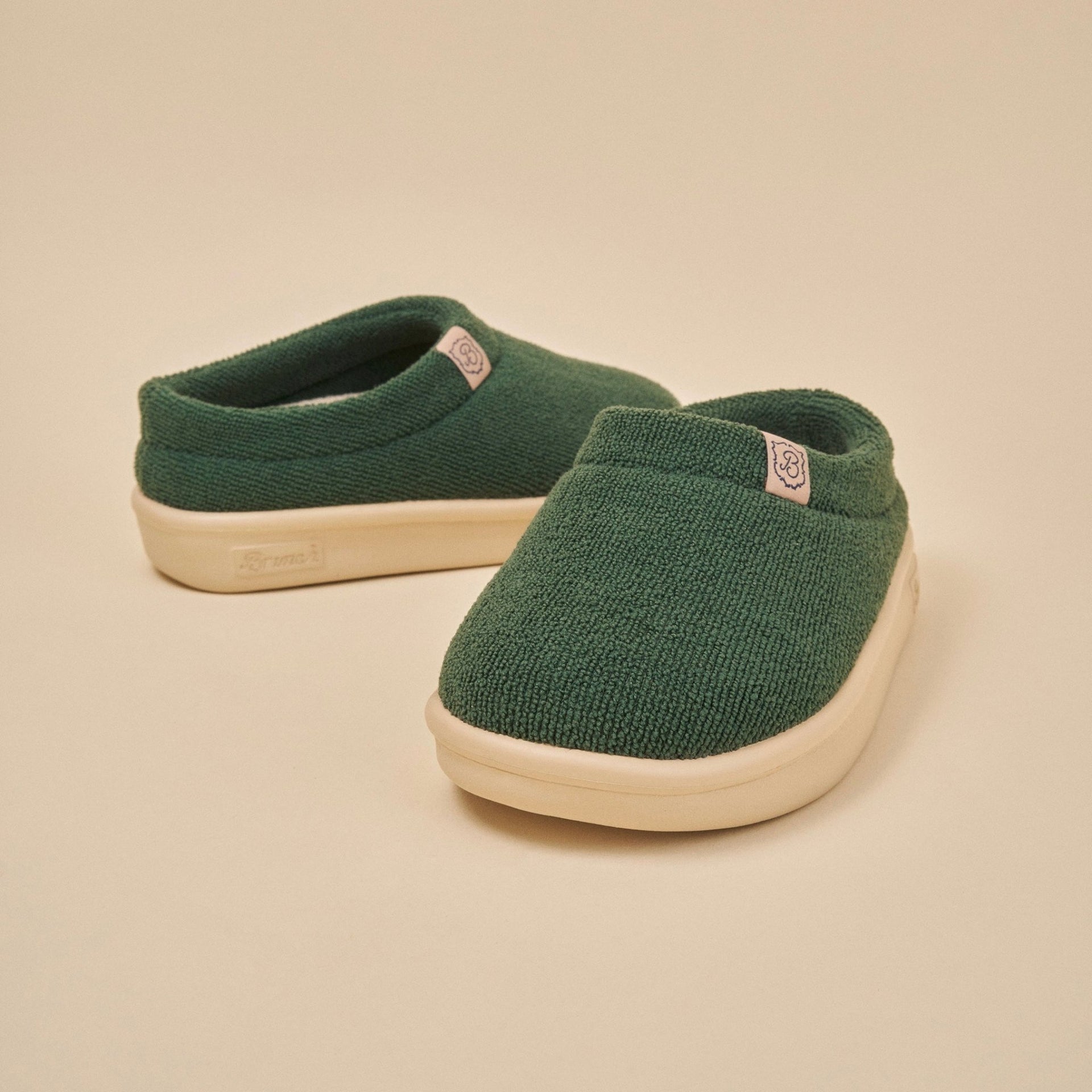 Front three-quarter view of Essential Kids slipper in emerald terry with cream EVA sole on beige background