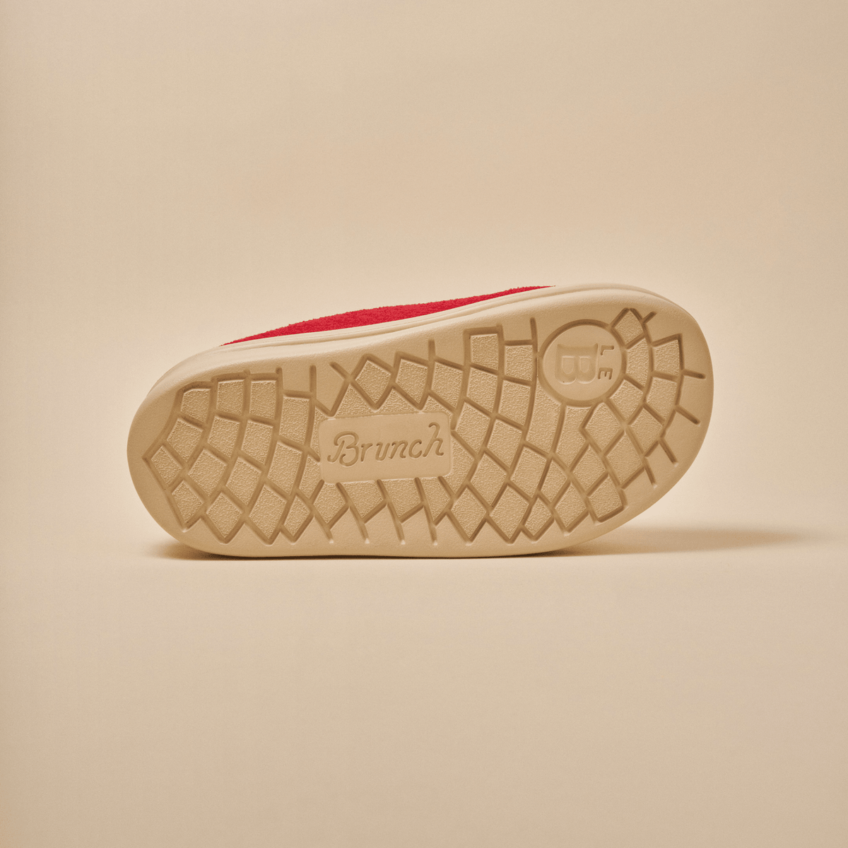 Sole view of Essential Kids slipper in red terry showcasing Brunch-branded textured EVA outsole on beige background