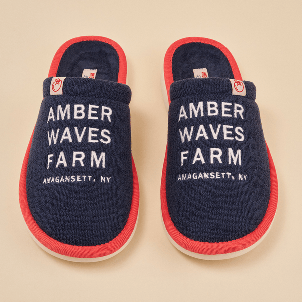 Top-down view of Essential slippers with navy terry upper, red trim, and white embroidered AMBER WAVES FARM text on beige