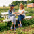 Two women sitting on a picnic bench at a farm, smiling and wearing navy Amber Waves Farm embroidered slippers