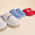Three-quarter front view of Essential Parke Varsity fleece slippers: gray pair with PARKE embroidery, denim-look blue pair, and red pair with white-heart motif on beige background
