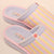 Top-down view of Cozyland Essential slipper, pastel rainbow stripes, soft terry lining, cushioned sole, sun motif tag on cream background