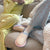 Three-quarter view of Cozyland Essential slipper showcasing pastel rainbow stripes and pink trim on a beige sofa