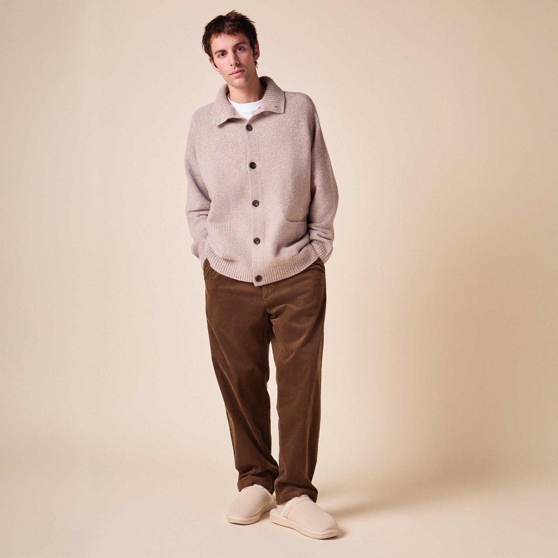 Front view of Essential Shearling slipper on model showcasing beige suede upper and plush shearling lining on neutral background
