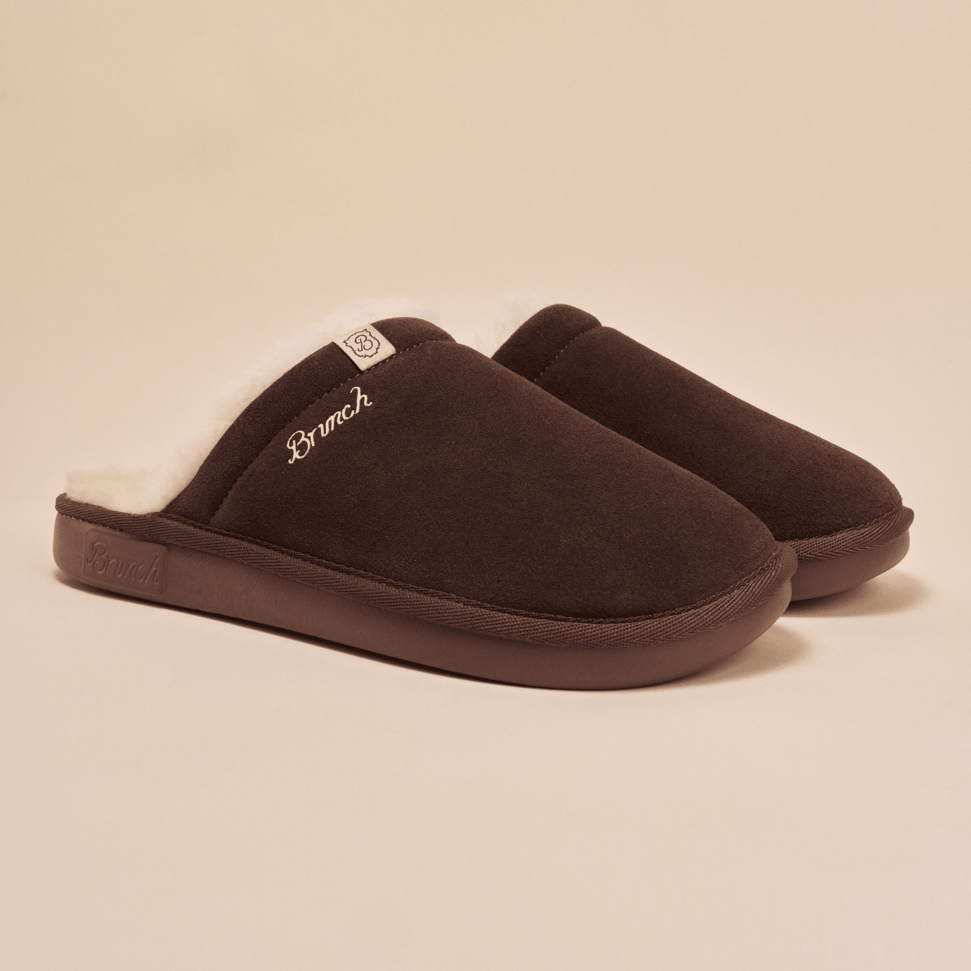 Angled view of Essential Shearling slipper showing brown suede upper, white shearling lining and Brunch embroidered logo