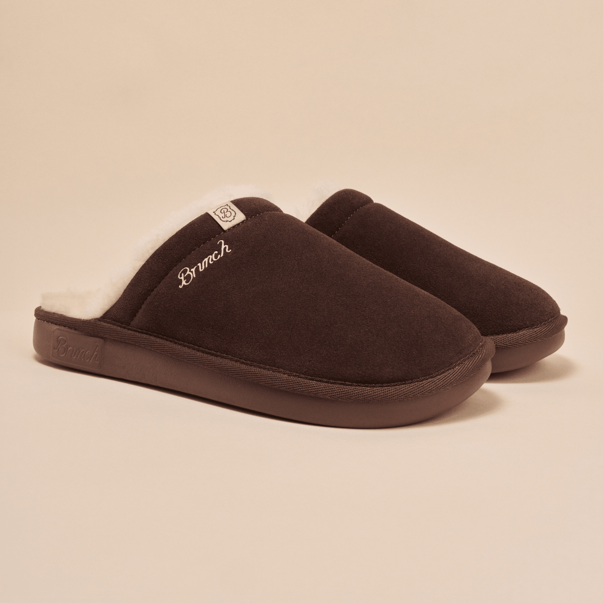 Angled view of Essential Shearling slipper showing brown suede upper, white shearling lining and Brunch embroidered logo