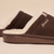 Close up side view of brown suede Essential Shearling slipper showing plush white shearling lining, Brunch embroidered logo and molded sole on beige background