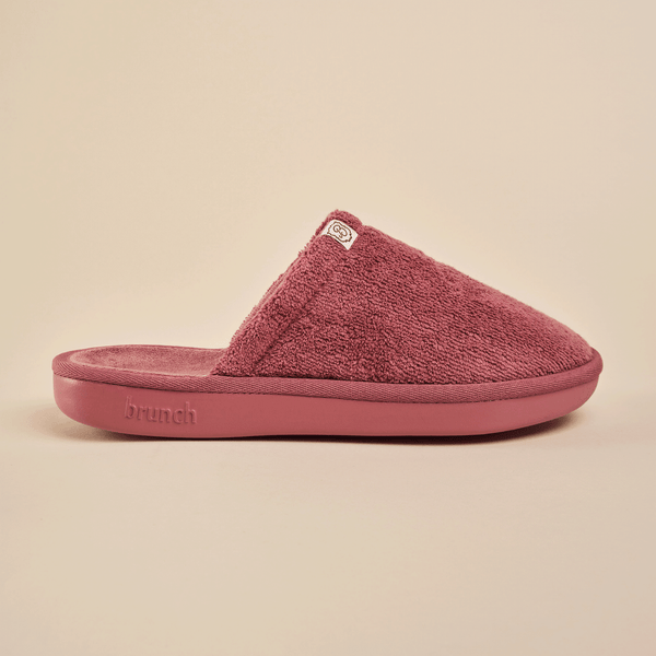 Side view of Essential Slipper showing plush terry upper, molded cushioned sole and Brunch logo on a neutral beige background