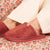Close-up side view of Essential Slipper in rose terry cloth showing plush upper, low Brunch rubber sole, on floral fabric