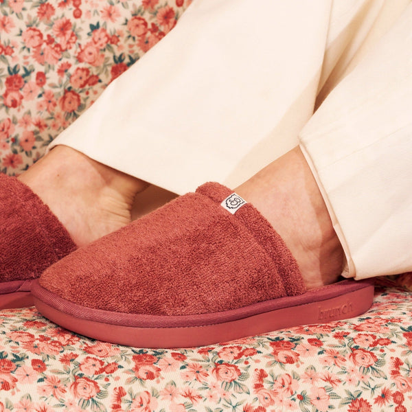 Close-up side view of Essential Slipper in rose terry cloth showing plush upper, low Brunch rubber sole, on floral fabric