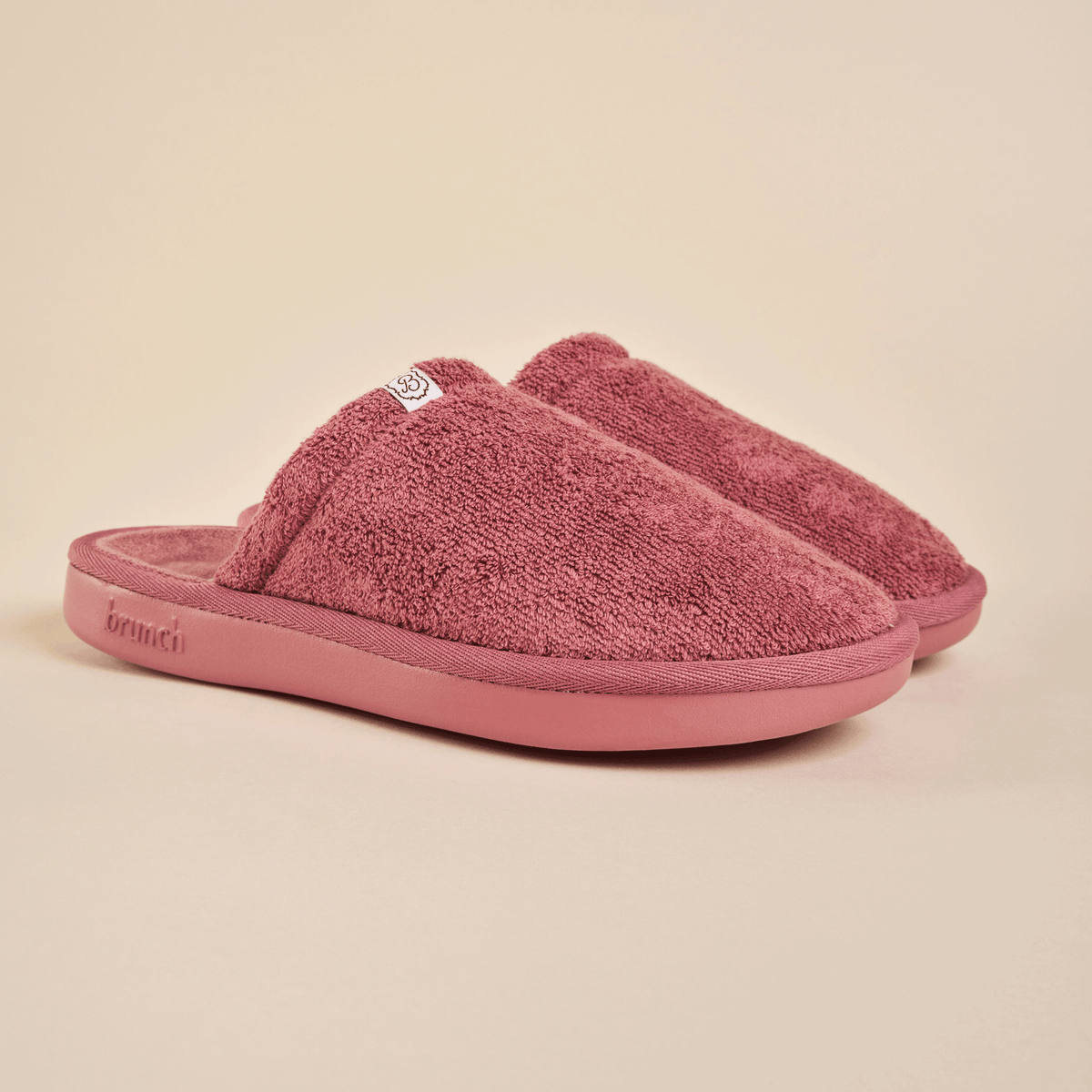 Three-quarter view of Essential Slipper in dusty rose terry cloth showcasing cushioned sole and open-back design on beige background