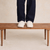 Front view of Essential Slipper in cream sherpa showcasing low-profile slip-on silhouette and cushioned sole on a wooden bench