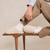 Side view of Essential slipper in cream showing plush boucle upper and low-profile sole, worn with white socks on wooden bench