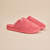 Three-quarter view of Essential Slipper in coral pink terry showing plush upper, open back and cushioned sole on beige