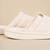 Close-up side view of cream Essential slipper showing terry-cloth upper and embossed brunch logo on the sole on a beige background