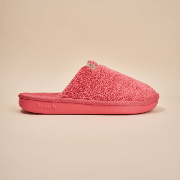 Side view of Essential Slipper in coral pink showcasing terry cloth upper and molded foam sole on neutral beige background