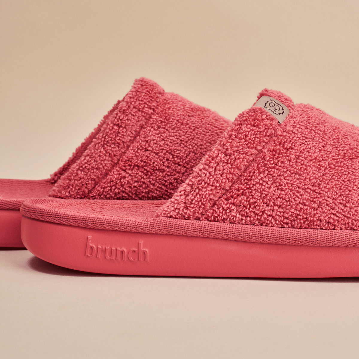 Side view of Essential slipper in pink showing plush terry upper and sole embossed with brunch on neutral background