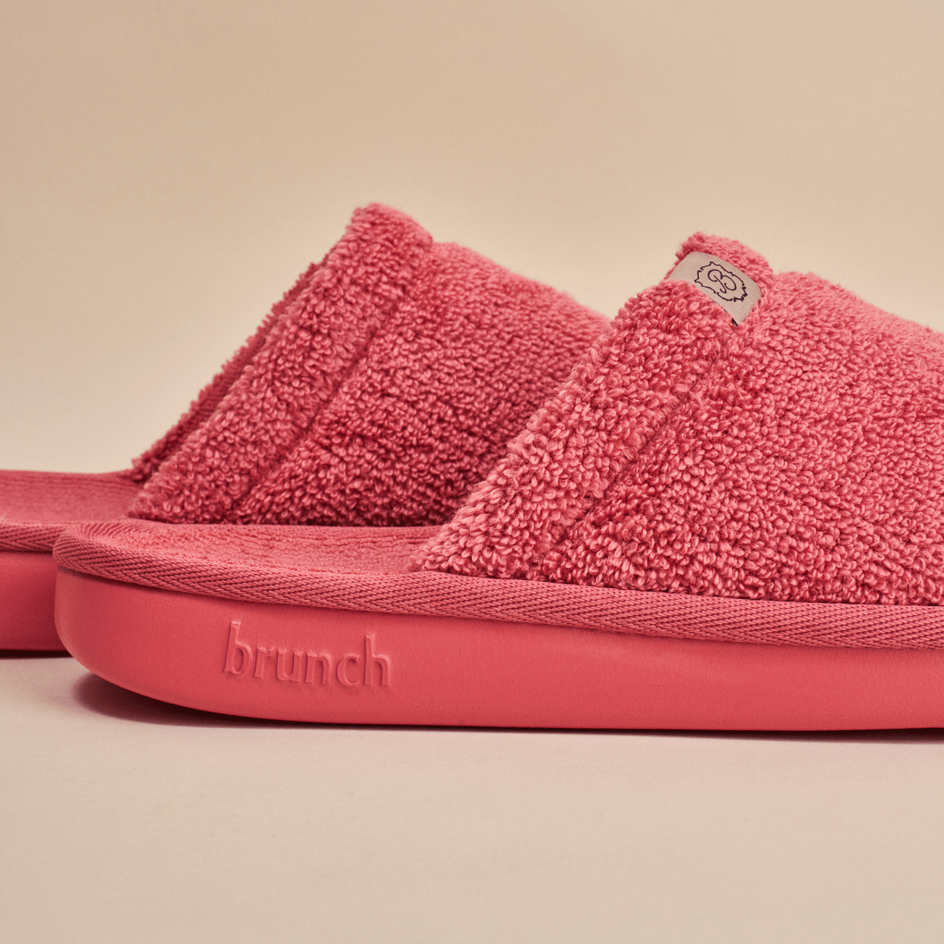 Side view of Essential slipper in pink showing plush terry upper and sole embossed with brunch on neutral background