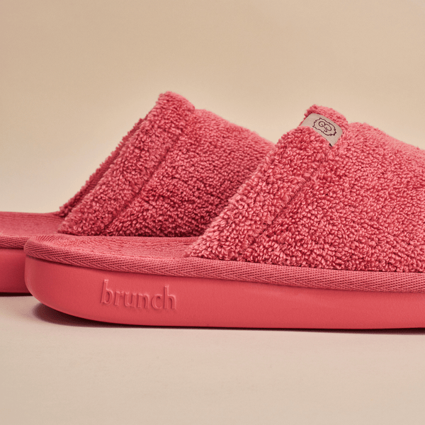 Side view of Essential slipper in pink showing plush terry upper and sole embossed with brunch on neutral background