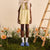 Front view of blue Essential slipper showcasing plush upper and slip-on sole on grassy floral backdrop