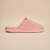 Side view of pink mule-style slipper showcasing terry cloth upper and cushioned molded sole on beige background