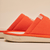 Side close up of White Lotus slipper in orange showing embroidered linen upper and embossed Brunch on cream EVA sole